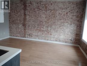 Peterborough (Town Ward 3) condo for rent - A room with a brick wall and wooden floor.