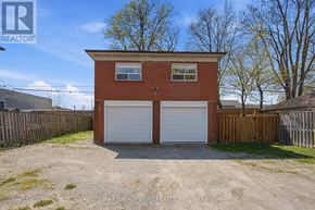 Toronto (Yorkdale-Glen Park) apartment for rent - A two-car garage is situated in a yard with a brick building and a wooden fence.