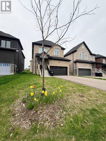 Innisfil (Lefroy) apartment for rent - A realtor photo of a house with a tree and flowers in the front yard.