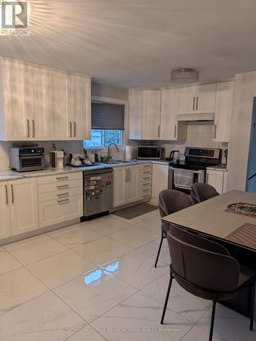 Mississauga (Rathwood) apartment for rent - A kitchen with white cabinets and a table with chairs.
