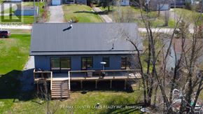 Kawartha Lakes (Carden) apartment for rent - A house with a metal roof and a deck is for sale.