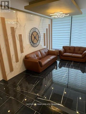 Toronto (Flemingdon Park) condo for rent - A living room with brown leather sofas and a marble wall.