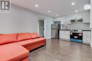 Toronto (Rouge) townhouse for rent - A living room with a red couch and a kitchen in the background.
