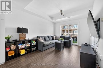 Lincoln (Beamsville) townhouse for rent - A living room with a grey sofa and a television on the wall.