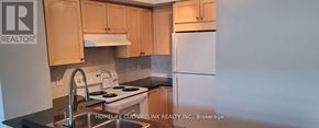 Toronto (Bayview Village) condo for rent - A kitchen with a white refrigerator and wooden cabinets.