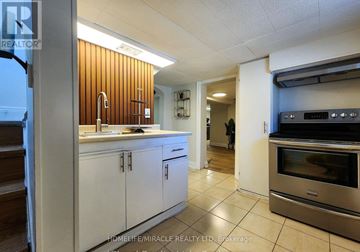 Hamilton (Homeside) apartment for rent - A kitchen with white cabinets and a wooden wall.