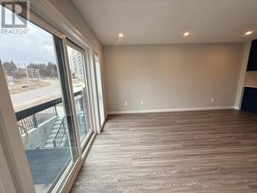 Kitchener townhouse for rent - A room with wooden flooring and a view of a construction site through the windows.