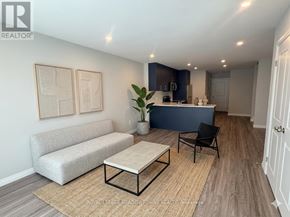 Kitchener townhouse for rent - A living room with a grey sofa, a coffee table, and a kitchen area in the background.