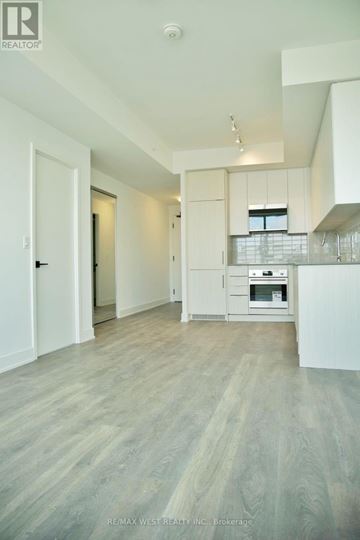 Oakville (Ro River Oaks) condo for rent - A spacious kitchen with white cabinets and a wooden floor.