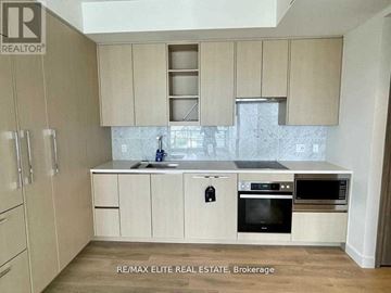 Toronto (Bayview Village) condo for rent - A kitchen with beige cabinets and a marble backsplash.