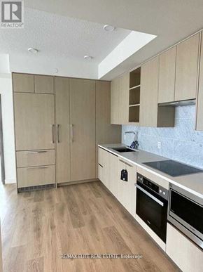 Toronto (Bayview Village) condo for rent - A kitchen with wooden cabinets and a marble backsplash.