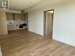 Toronto (Bayview Village) condo for rent - A spacious room with wooden flooring and a kitchen area in the background.