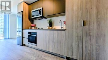 Toronto (Newtonbrook West) condo for rent - A modern kitchen with wooden cabinets and a stainless steel refrigerator.