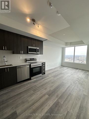 Pickering (Bay Ridges) condo for rent - A modern kitchen with dark wood cabinets and stainless steel appliances.