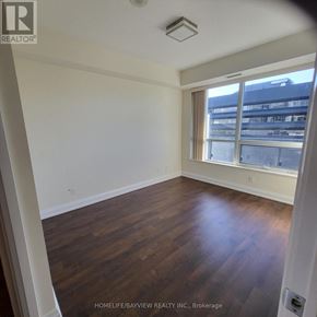 Toronto (Willowdale East) condo for rent - A room with wooden floors and a window overlooking a cityscape.