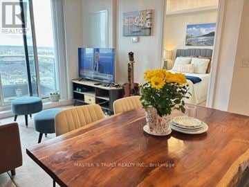 Richmond Hill (Langstaff) condo for rent - A living room with a wooden table and a television on a stand.