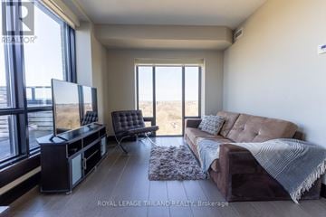 London East (East B) condo for rent - A living room with a brown couch and a flat screen TV.
