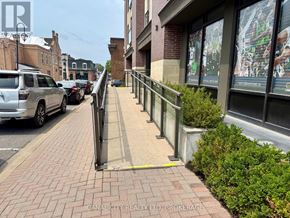 Thorold (Thorold Downtown) apartment for rent - A street view with a sidewalk, a car, and a building with a large window displaying a basketball game.