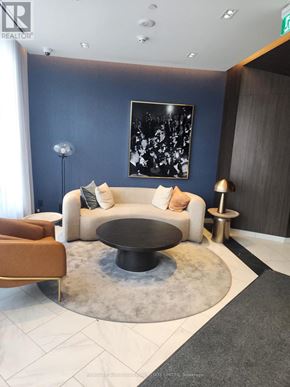 Toronto (Annex) condo for rent - A modern living room with a white couch, a black coffee table, and a large abstract painting on the wall.