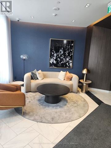 Toronto (Annex) condo for rent - A modern living room with a white couch, a black coffee table, and a large abstract painting on the wall.