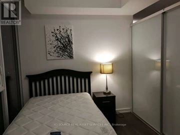 Toronto (Kensington-Chinatown) condo for rent - A bedroom with a white bed and a black and white painting on the wall.