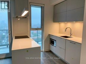 Toronto (Waterfront Communities) condo for rent - A modern kitchen with white cabinets and a large window.