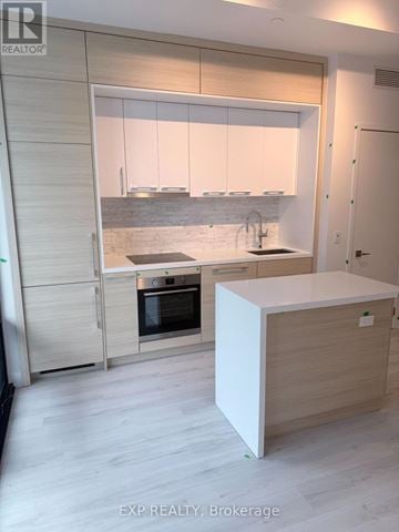 Toronto (Bayview Village) condo for rent - A modern kitchen with a white island and wooden cabinets.