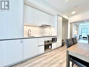 Vaughan (Vaughan Corporate Centre) condo for rent - A modern kitchen with white cabinets and a wooden table.