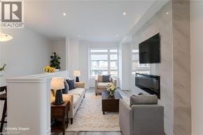 Paris townhouse for rent - A living room with a white sofa, a grey armchair, a coffee table, and a flat-screen TV mounted on the wall.