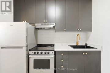 London East (East F) multi-family for rent - A kitchen with a white fridge, black oven and sink.