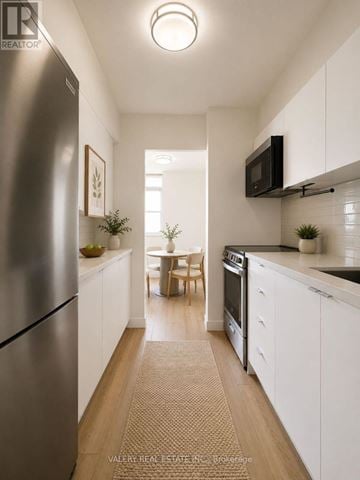Mississauga (Port Credit) condo for rent - A kitchen with white cabinets and a stainless steel refrigerator.