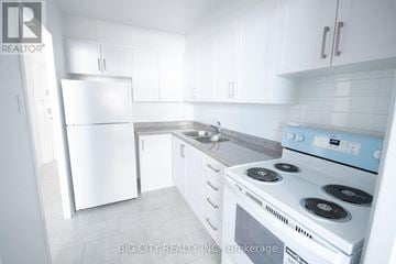 Toronto (East York) condo for rent - A white kitchen with a stove and a refrigerator.