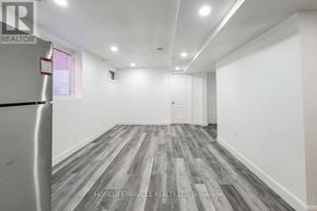 Hamilton (Stoney Creek) apartment for rent - A spacious room with wooden flooring and white walls.