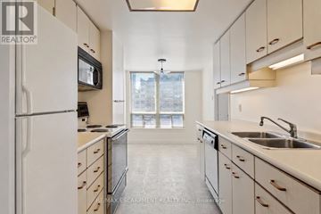 Burlington (Brant) condo for rent - A kitchen with white cabinets and a black microwave.
