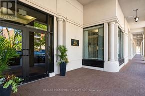 Burlington (Brant) condo for rent - The image shows the entrance to a building with a glass door and a sign that reads "RE/MAX ESCARPMENT REALTY INC.. Brokerage".