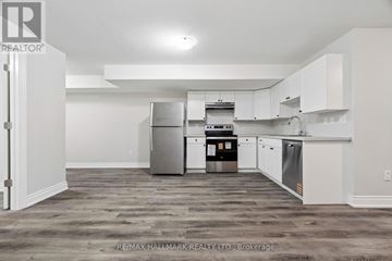 Toronto (Mimico) apartment for rent - A kitchen with white cabinets and a grey floor.