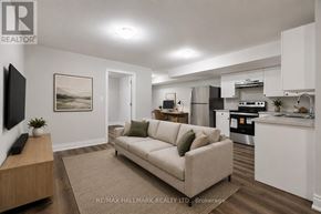 Toronto (Mimico) apartment for rent - A modern living room with a couch, a television, and a kitchen area in the background.