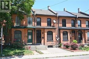 Hamilton apartment for rent - A row of red brick houses with green doors and windows.