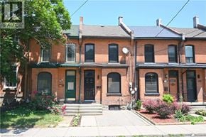 Hamilton apartment for rent - A row of red brick houses with green doors and windows.