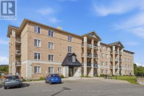 Guelph (Kortright West) condo for rent - A multi-story apartment building with a parking lot in front.