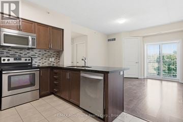 Guelph (Kortright West) condo for rent - A kitchen with a stove top oven, microwave, and dishwasher.