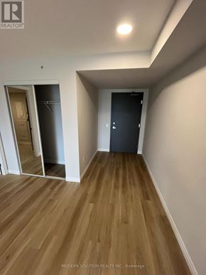 Guelph (Grange Road) condo for rent - A room with wooden flooring and two doors, one open to a hallway and one closed.