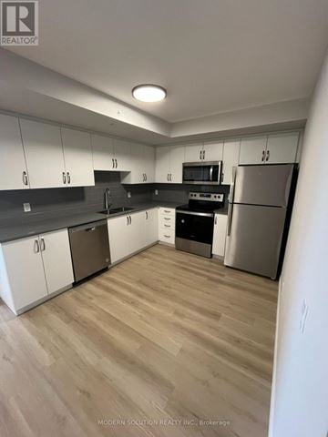 Guelph (Grange Road) condo for rent - A kitchen with white cabinets and stainless steel appliances.