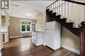 Port Coquitlam apartment for rent - A white refrigerator is in a kitchen with wood floors and a staircase.