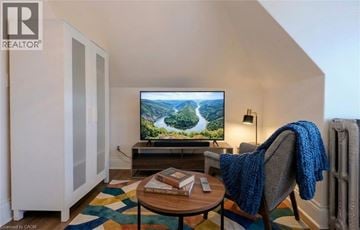 Hamilton apartment for rent - A living room with a television on a stand and a chair with a blue blanket on it.