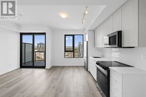 Burlington (Brant) condo for rent - A modern kitchen with white cabinets and a black countertop.