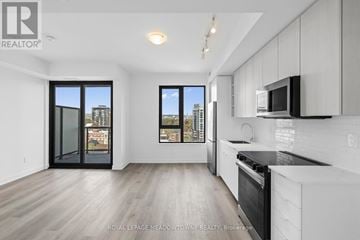 Burlington (Brant) condo for rent - A modern kitchen with white cabinets and a black countertop.