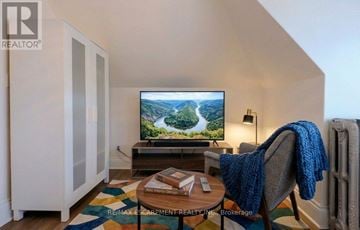 Hamilton (Blakeley) apartment for rent - A living room with a television on a stand and a chair with a blue blanket on it.