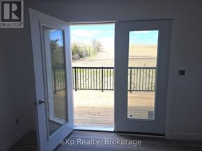South Bruce multi-family for rent - A white door with a glass window is open to a balcony with a black railing.
