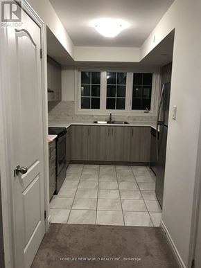 Oshawa (Windfields) townhouse for rent - A kitchen with white cabinets and a white door.